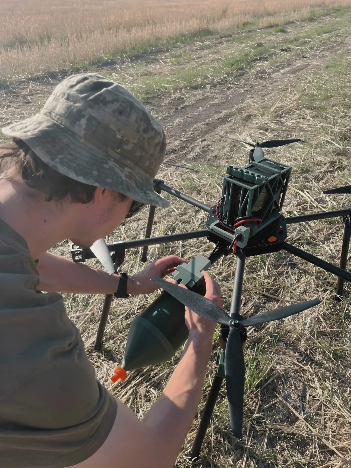 Operator attaching an OPTAC fiber optic spool to a UAV in the field